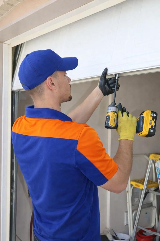 A technician from Titan Garage Doors CO repairing a broken garage door in Drake, CO